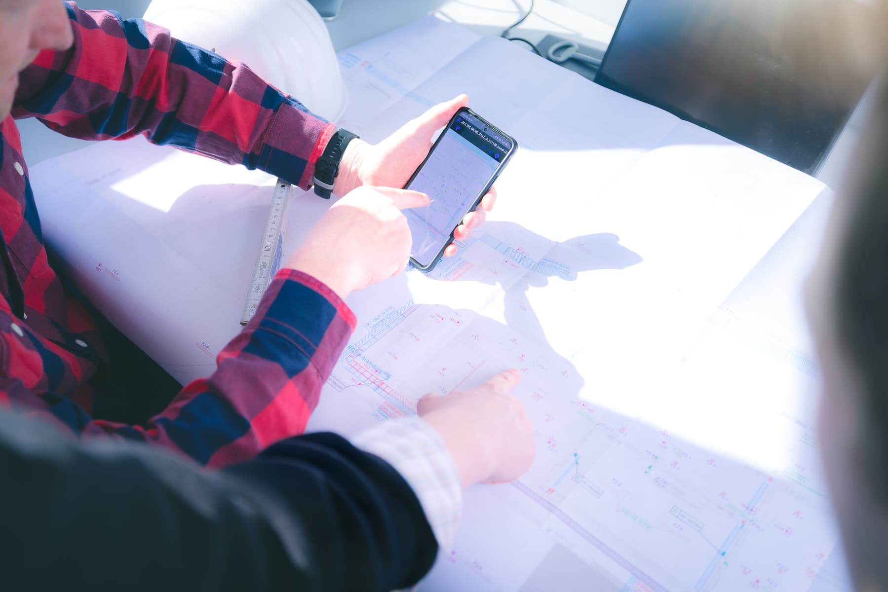 Digitale Bauplanung — Smartphone mit Plan-App über einem gedruckten Bauplan beim IK-Ingenieurbüro Knoblich Dresden