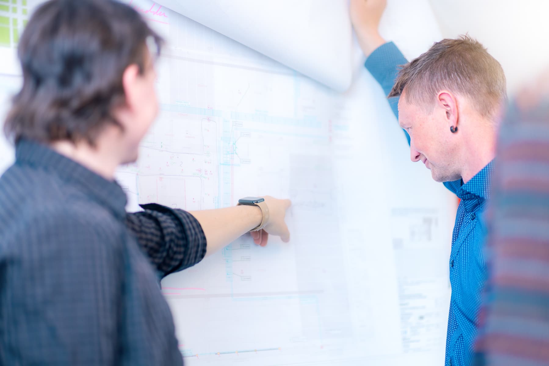 TGA-Fachplaner bei der Planabstimmung an einer Elektroplan-Wandzeichnung beim IK-Ingenieurbüro Knoblich Dresden